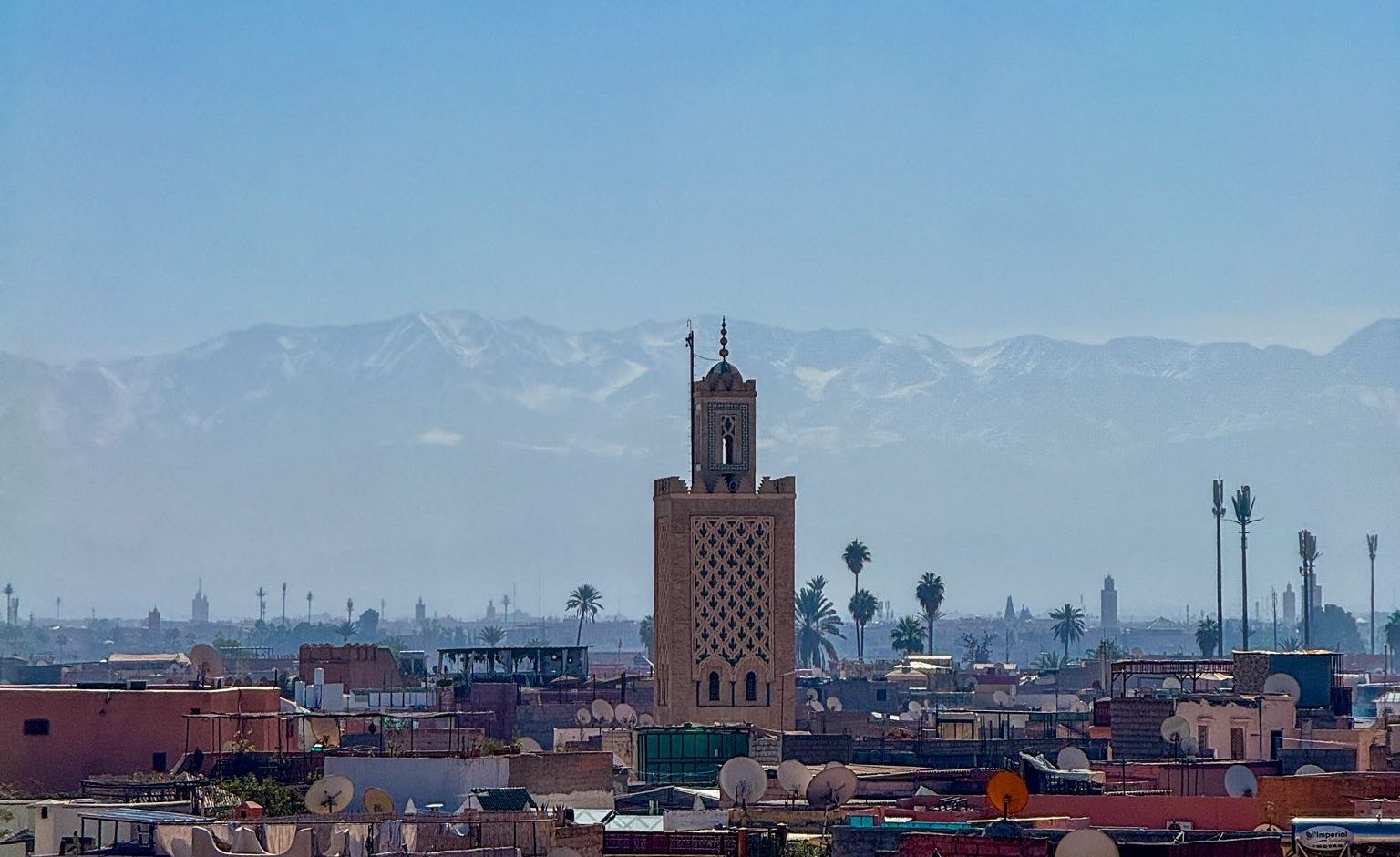 View of Marrakech and Atlas Mountains, huge Mosque in the middle.
