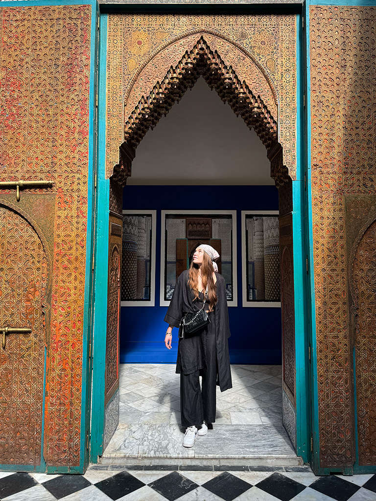 Museum in Marrakesch: Frau blickt wunderschön verschnörkelte Tür an